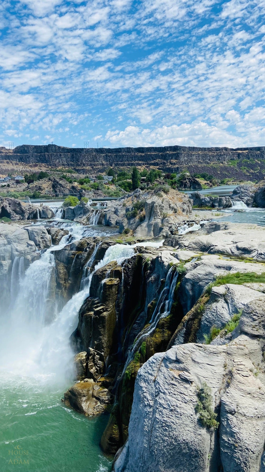 Waterfalls cascading through a rocky canyon beneath a bright blue sky